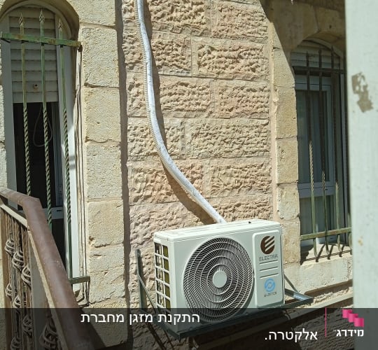 יחידת מיזוג אוויר מותקנת על קיר חיצוני של בניין.
